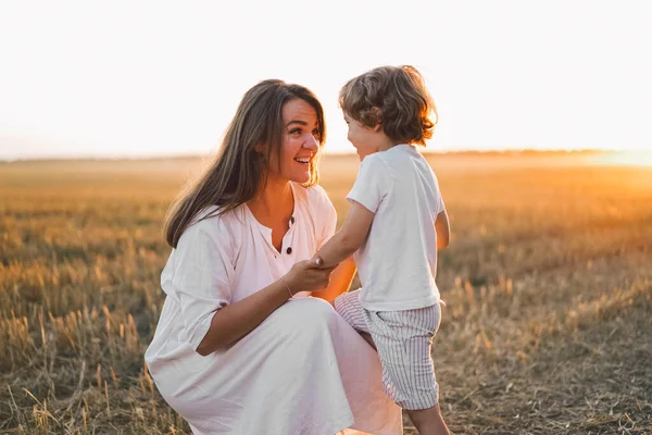 Vrouw spelen met haar kind op het veld tijdens zonsondergang — Stockfoto