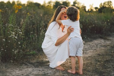 Gün batımında sahada çocuğuyla oynayan bir kadın.