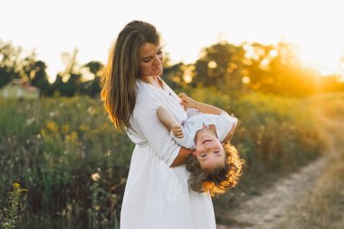 Gün batımında sahada çocuğuyla oynayan bir kadın.