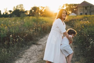 Gün batımında sahada çocuğuyla oynayan bir kadın.