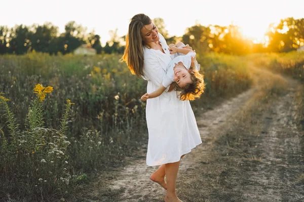 Gün batımında sahada çocuğuyla oynayan bir kadın.