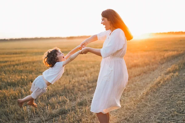 Donna che gioca con il suo bambino sul campo durante il tramonto — Foto Stock