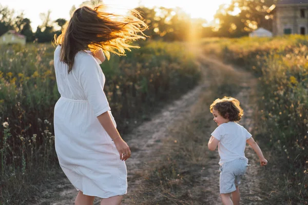 Donna che gioca con il suo bambino sul campo durante il tramonto — Foto Stock