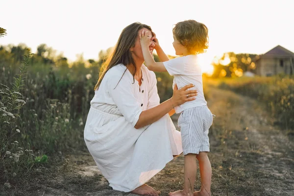 Donna che gioca con il suo bambino sul campo durante il tramonto — Foto Stock