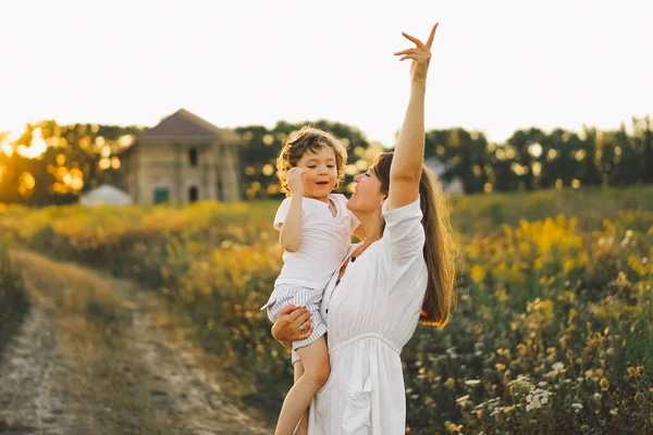 Mulher brincando com seu filho no campo durante o pôr do sol — Fotografia de Stock