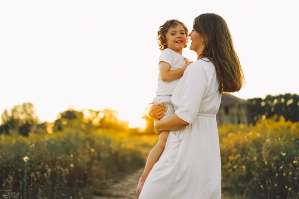 Donna che gioca con il suo bambino sul campo durante il tramonto — Foto Stock