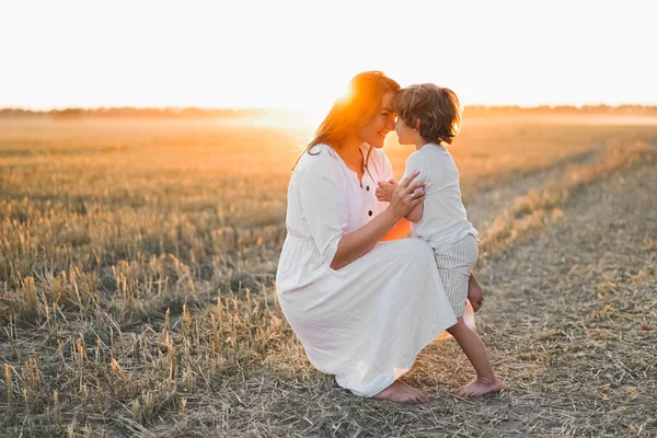 Gün batımında sahada çocuğuyla oynayan bir kadın.