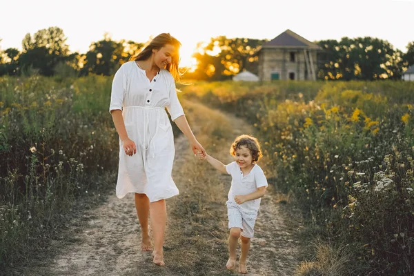 Gün batımında sahada çocuğuyla oynayan bir kadın.