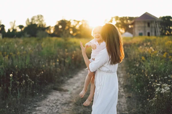 Gün batımında sahada çocuğuyla oynayan bir kadın.