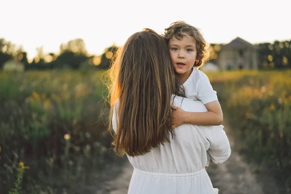 Donna che gioca con il suo bambino sul campo durante il tramonto — Foto Stock