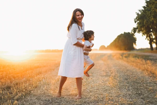 Donna che gioca con il suo bambino sul campo durante il tramonto — Foto Stock