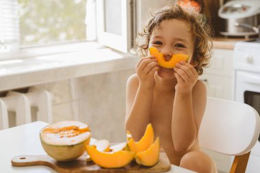 Tatlı, güzel bir çocuk taze kavun yiyor. Sağlıklı gıda, çocukluk ve gelişme. 