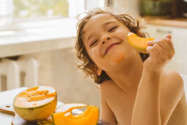 Tatlı, güzel bir çocuk taze kavun yiyor. Sağlıklı gıda, çocukluk ve gelişme. 