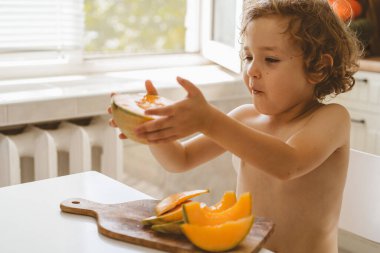 Tatlı, güzel bir çocuk taze kavun yiyor. Sağlıklı gıda, çocukluk ve gelişme. 