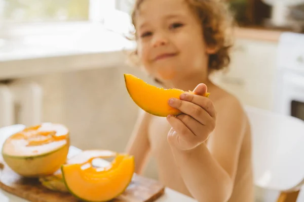 Lindo niño hermoso comiendo melón fresco. Alimentación saludable, infancia y desarrollo. — Foto de Stock