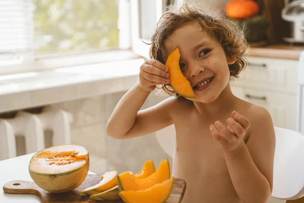 Lindo niño hermoso comiendo melón fresco. Alimentación saludable, infancia y desarrollo. —  Fotos de Stock