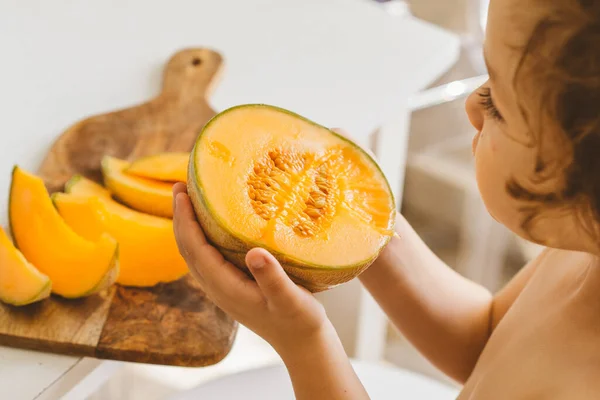 Lindo niño hermoso comiendo melón fresco. Alimentación saludable, infancia y desarrollo. —  Fotos de Stock