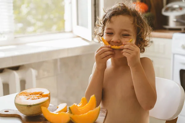 Lindo niño hermoso comiendo melón fresco. Alimentación saludable, infancia y desarrollo. —  Fotos de Stock