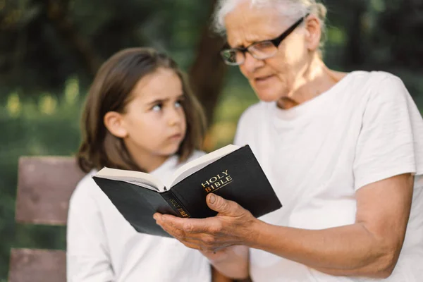 Grandmother and little girl reading holy bible. Study the holy bible together