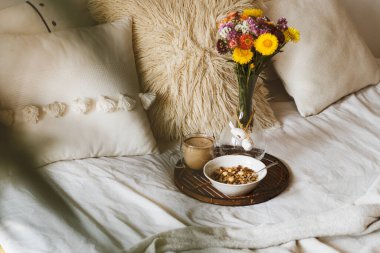 Kahve fincanı ve tepside granola ile yatakta kahvaltı. Uzayı kopyala Sıcak kahvaltı.