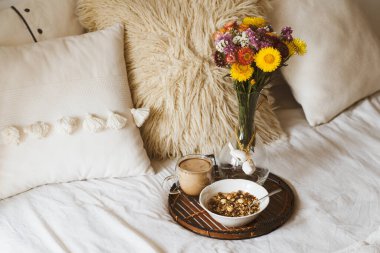 Kahve fincanı ve tepside granola ile yatakta kahvaltı. Uzayı kopyala Sıcak kahvaltı.