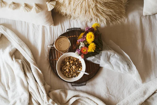 Kahve fincanı ve tepside granola ile yatakta kahvaltı. Uzayı kopyala Sıcak kahvaltı.