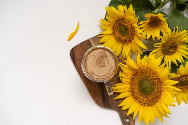 Ein Strauß großer Sonnenblumen und heißer Kaffee. Sonnenblumen Anordnung flach legen Stil auf Hintergrund weiß — Stockfoto