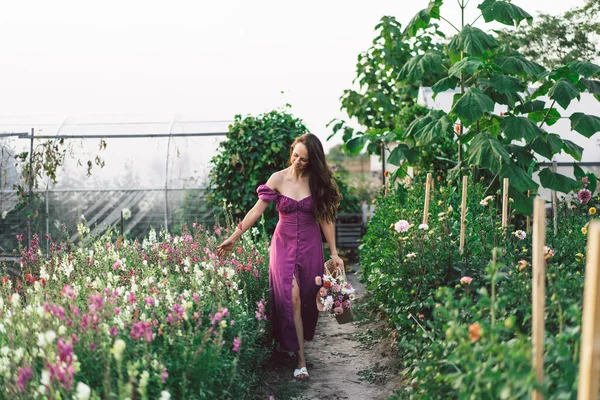 Retrato chica con el pelo largo con una cesta de flores. Camina por el jardín de flores. Chica y flores — Foto de Stock
