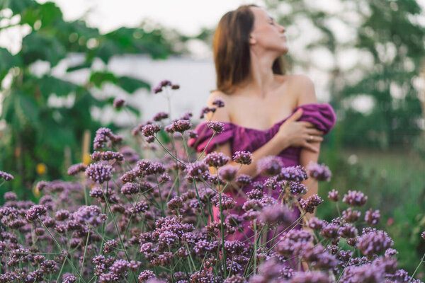 Portrait of a girl out of focus in purple flowers. Walk in the flower garden. Girl and flowers