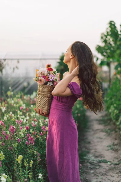 Πορτρέτο κορίτσι με μακριά μαλλιά με καλάθι με λουλούδια. Περπατήστε στον κήπο με τα λουλούδια. Κορίτσι και λουλούδια — Φωτογραφία Αρχείου