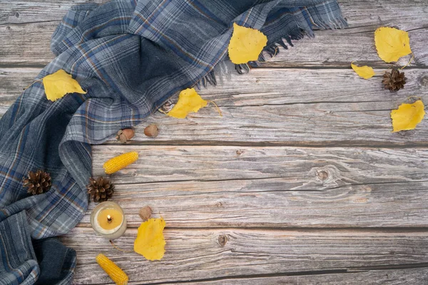 Őszi lapos feküdt szürke sál, gyertya és száraz levelek sárga színű fa háttér. — Stock Fotó