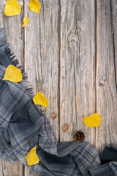 Hösten platt låg med grå halsduk och torra blad av gul färg på trä bakgrund. — Stockfoto