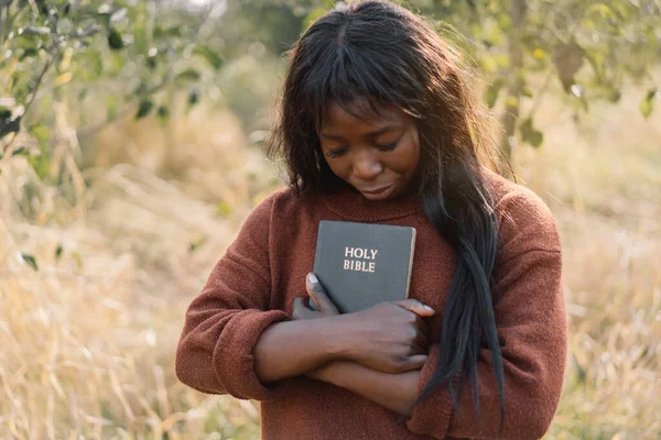 Křesťanská afro dívka drží Bibli ve svých rukou. Čtu Bibli svatou. Koncept víry. — Stock fotografie