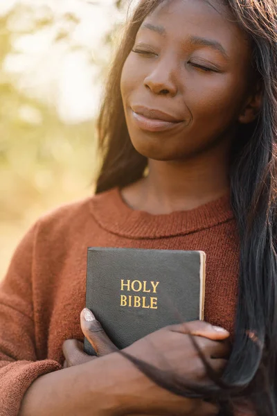 Christian afro girl tient la bible dans ses mains. Lire la Sainte Bible. Concept de foi. Images De Stock Libres De Droits