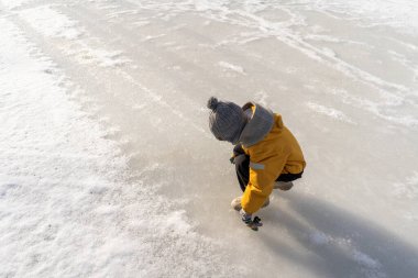 Child having fun in the snow, wearing winter clothing in snowy landscape during daytime. Child with a big smile surrounded by snowy trees and a clear blue sky.