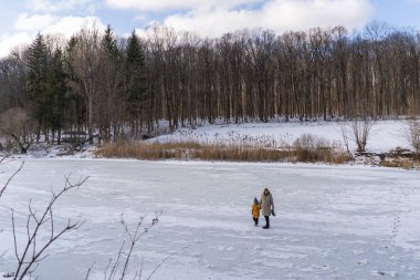 In a serene winter forest, a son and father have a great time, both dressed in warm clothes. The scene captures a moment of love against a snowy backdrop, evoking warmth and connection. Fathers Day