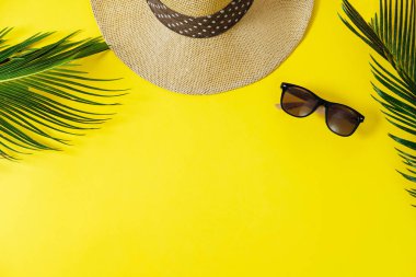 Seyahat kavramı: şapka, sarı arka plan palmiye yaprağı ve Güneş gözlükleri. Üstten Görünüm, düz yatıyordu, metin için yer