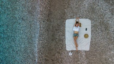 Plaj havlusu üzerinde şort ve yelek sahilde tatil kadınla. Uçak fotoğraf. Top havadan görünümü 