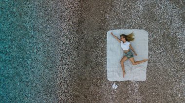 Komik kadın üst hava görünümünü bir plaj havlusu üzerinde şort ve yelek plajında. Uçak fotoğraf