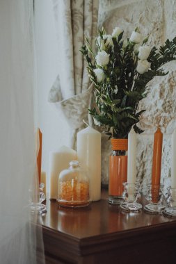 Beyaz ve turuncu mum ve bir buket çiçek masada