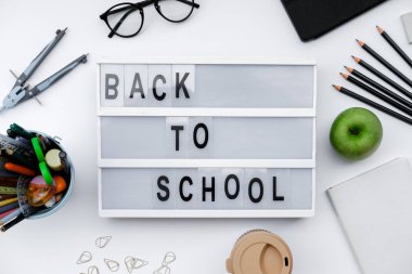 Okul malzemeleri ve beyaz masa üzerinde yeşil elma ile blok okul için geri. Üstten görünüm, düz la