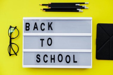 Sarı zemin üzerine okul malzemeleri ile blok okul için geri. Üstten görünüm, düz la