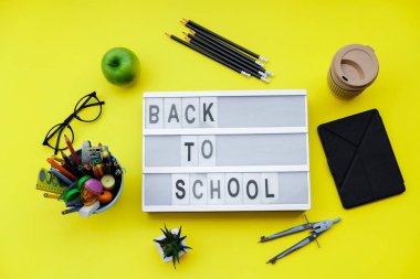 Sarı zemin üzerine okul malzemeleri ile blok okul için geri. Üstten görünüm, düz la