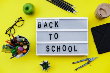 Sarı zemin üzerine okul malzemeleri ile blok okul için geri. Üstten görünüm, düz la