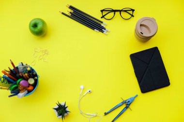 Geri okul ile arka plan için sarı masa üzerinde okul malzemeleri. Üstten görünüm, düz la