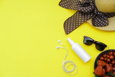 Yaz zemin üzerine sarı tablo: Straw Hat, soda, çilek güneş kremi ve gözlük. Üstten görünüm, düz yatıyordu