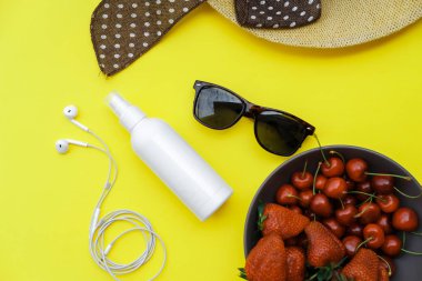 Yaz zemin üzerine sarı tablo: Straw Hat, soda, çilek güneş kremi ve gözlük. Üstten görünüm, düz yatıyordu