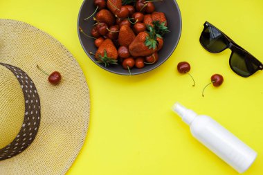 Yaz zemin üzerine sarı tablo: Straw Hat, soda, çilek güneş kremi ve gözlük. Üstten görünüm, düz yatıyordu