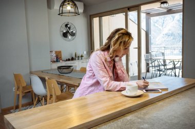 Güzel genç kadın serbest meslek sahibi bir apartman dairesinde telefon ve defter ile çalışır. İş concep