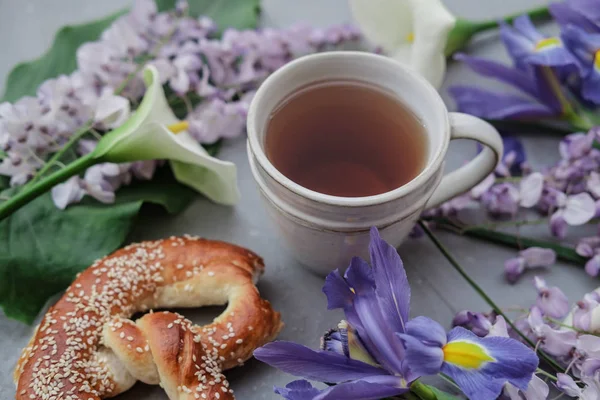 Herbal tea with wisteria, irises, white callas on gray background.